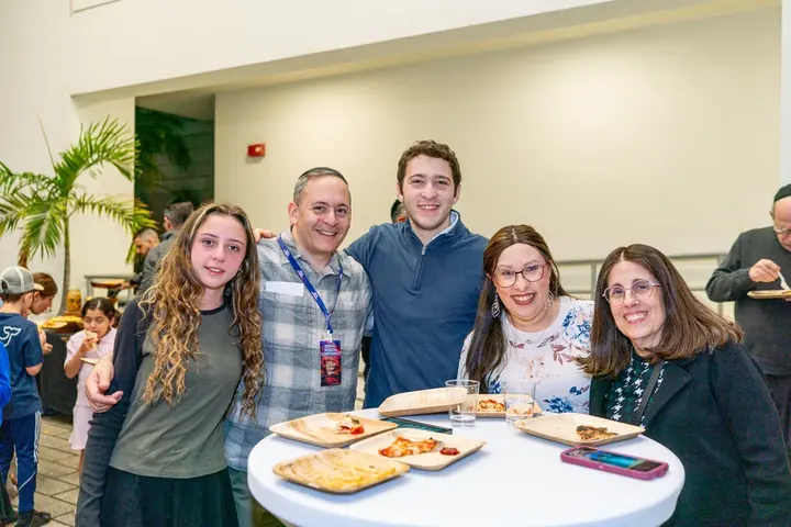 Group of five attendees and family members smiling together at a conference social event