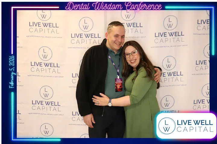 Couple posing at the LiveWell Capital sponsor photo booth at the Dental Wisdom Conference