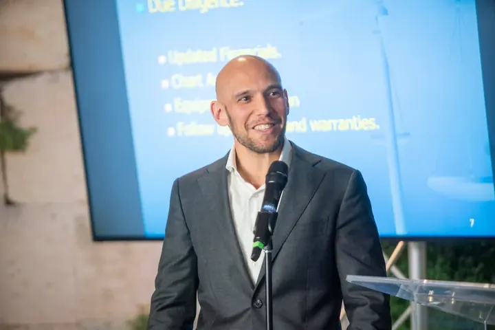 Speaker smiling at the microphone presenting in front of a financial due diligence slide