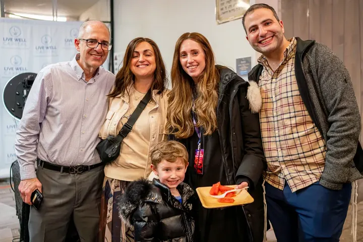 Group of four adults and a young child posing and smiling at a conference social event