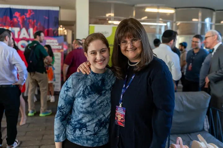 Two women smiling together at the conference with the Dental Wisdom Conference banner visible in the background