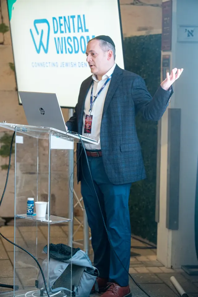 Conference organizer speaking at the podium in front of the Dental Wisdom logo