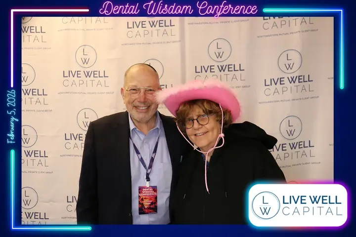 Two attendees posing at the LiveWell Capital sponsor photo booth at the Dental Wisdom Conference