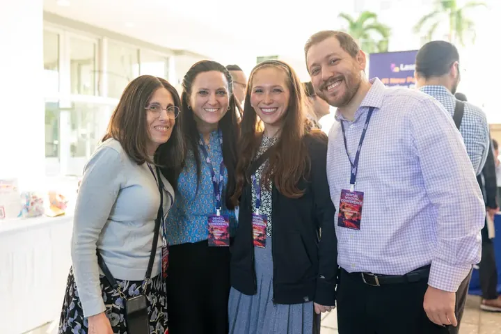 Four smiling conference attendees posing together wearing Dental Wisdom lanyards