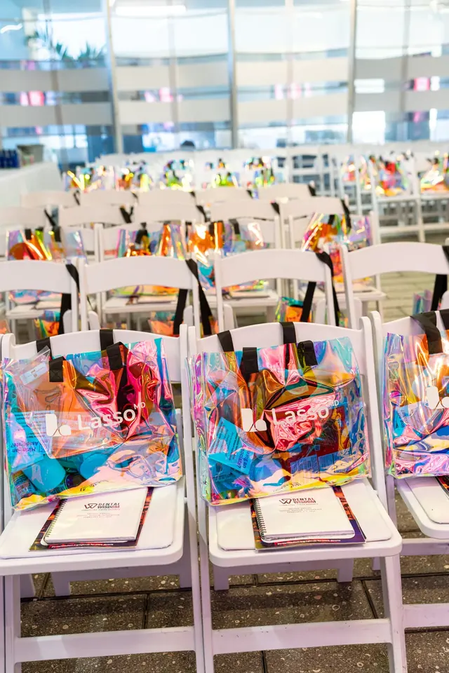 Rows of white chairs with holographic Lasso MD gift bags and Dental Wisdom notebooks set out for attendees