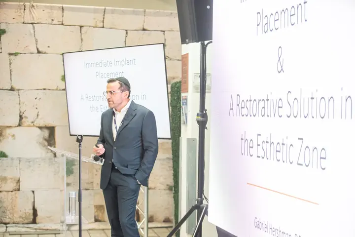 Speaker presenting on immediate implant placement and esthetic zone restoration at the conference
