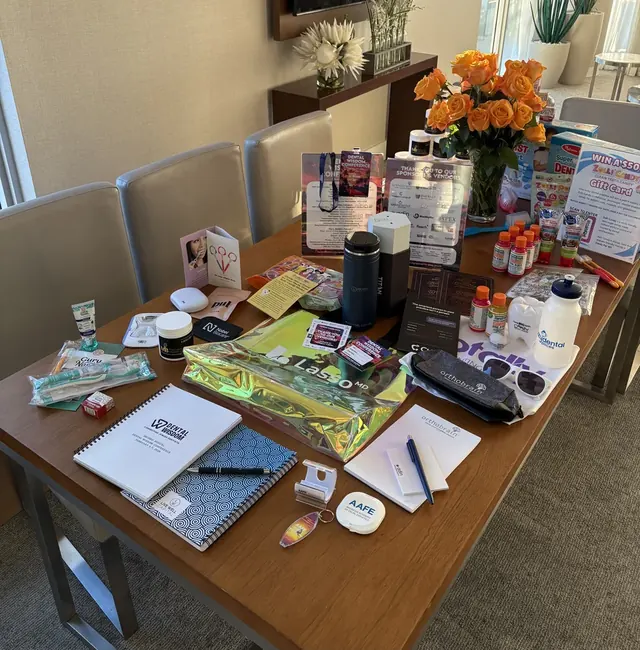 Table displaying conference gift bag contents including dental products, notebooks, and branded sponsor giveaways