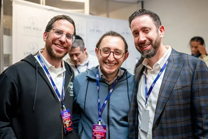 Three smiling male attendees wearing Dental Wisdom conference lanyards