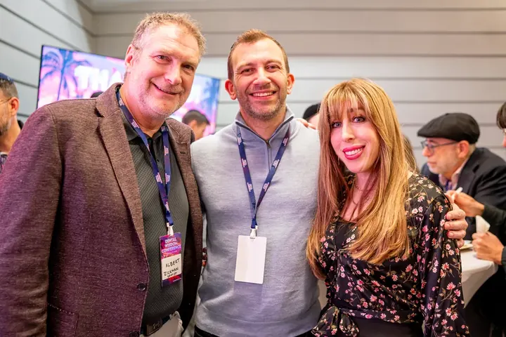Three attendees posing and smiling at a conference social event