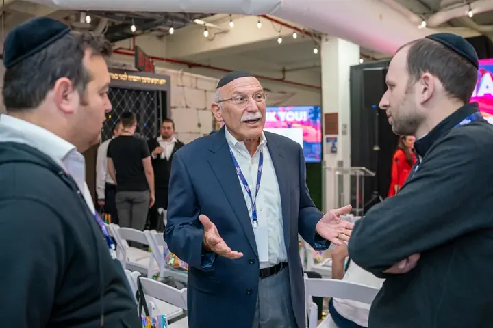 Three attendees in animated conversation at a conference social event
